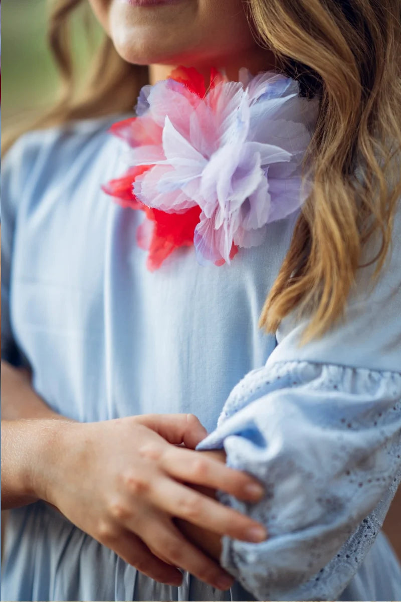 Child wearing an elegant light blue a-line dress with a colorful floral accessory, showcasing style and charm.