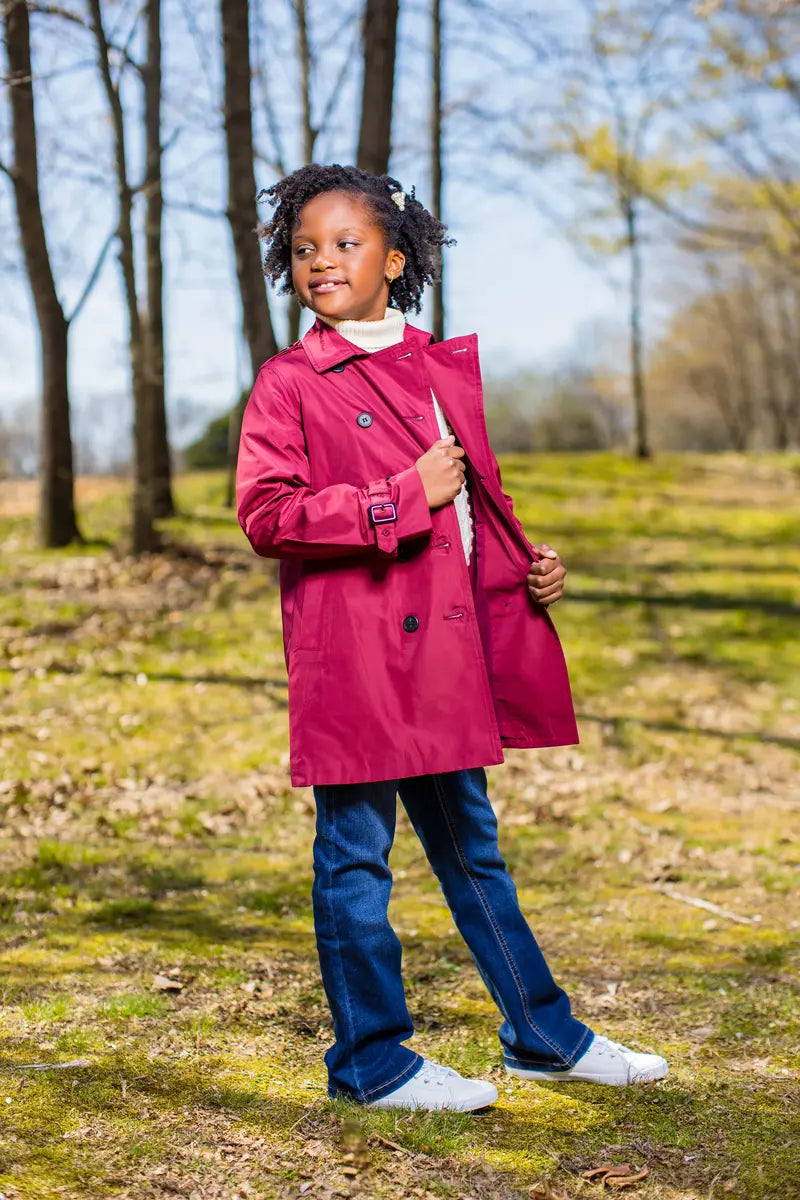 Girl wearing a rich berry trench coat in a wooded area, showcasing style and warmth for cooler months.