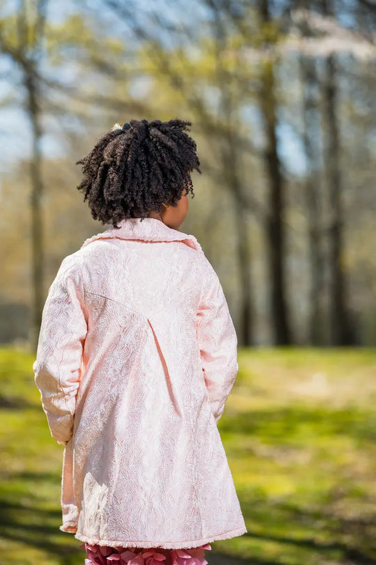 girl wearing a light pink embroidered coat outdoors in spring