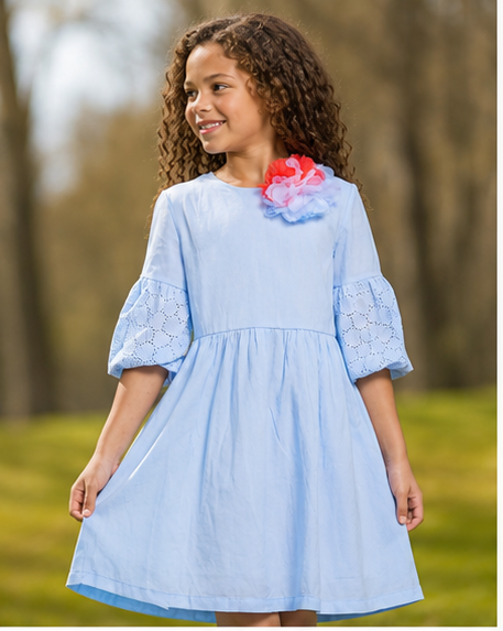 A young girl wearing an elegant light blue a-line dress with floral accents, perfect for spring outings.