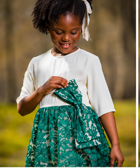 A girl wearing a white and green lace dress, smiling and holding a bow, perfect for a special occasion. white teal blouson party dress