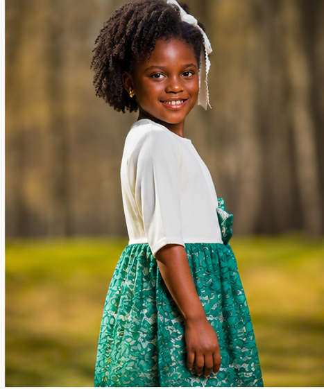 White teal blouson party dress on a smiling girl, featuring a blouson silhouette and vibrant teal lace details.