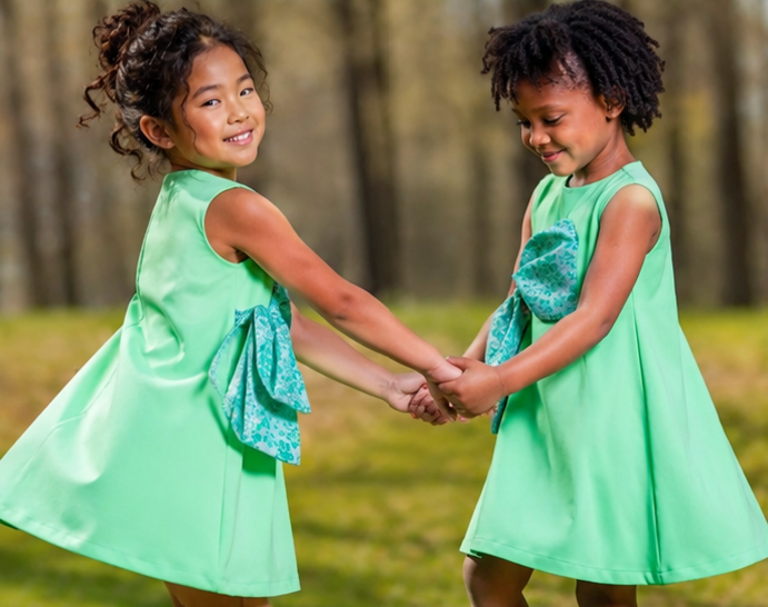 olive green party dress with cyan bow worn by girls in a sunny outdoor setting, showcasing joyful friendship.