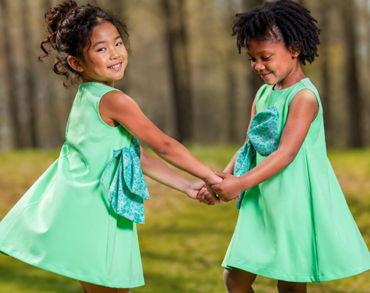 olive green party dress with cyan bow worn by girls in a sunny outdoor setting, showcasing joyful friendship.